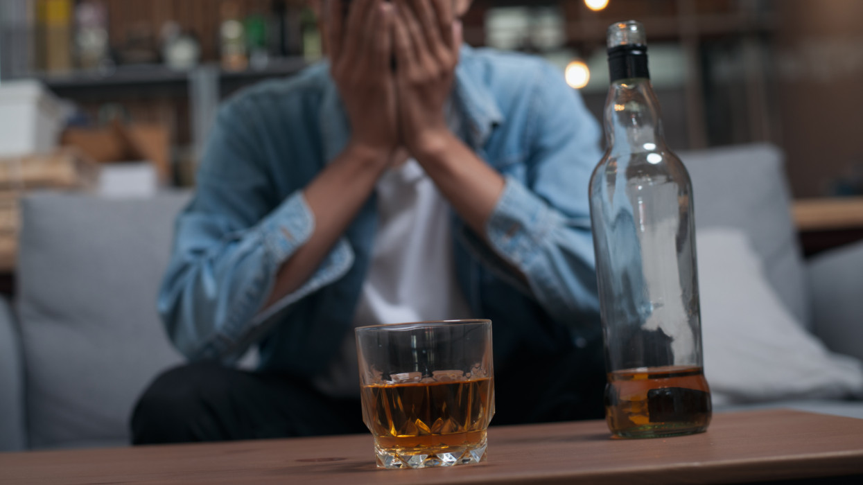 Alcoholism or Alcoholic concept : Close up young Asian guy feeling depressed drinking alcohol alone in pub or bar because life problem or stress.