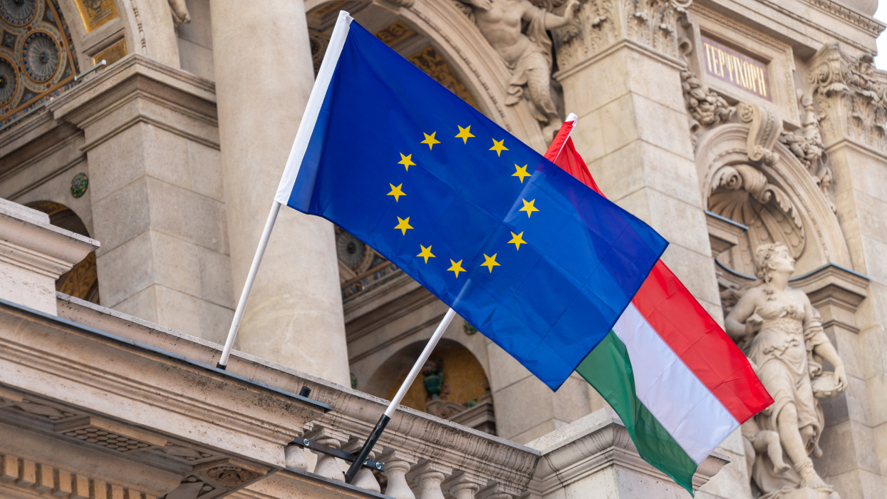 Flags of the European Union and Hungary flying from poles outside an ornate building in the centre of Hungarian capital city of Budapest