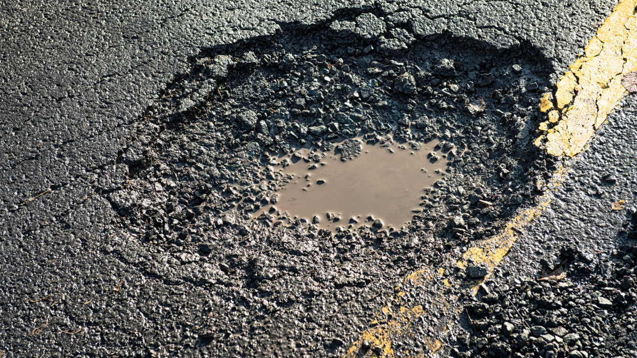 Close-up of the effects of road weathering and neglect - a deep pot hole causing a danger to drivers.