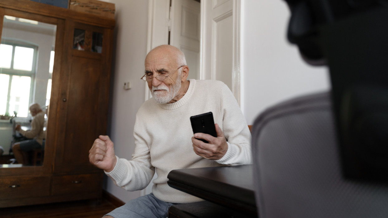 Elderly man using smartphone at home