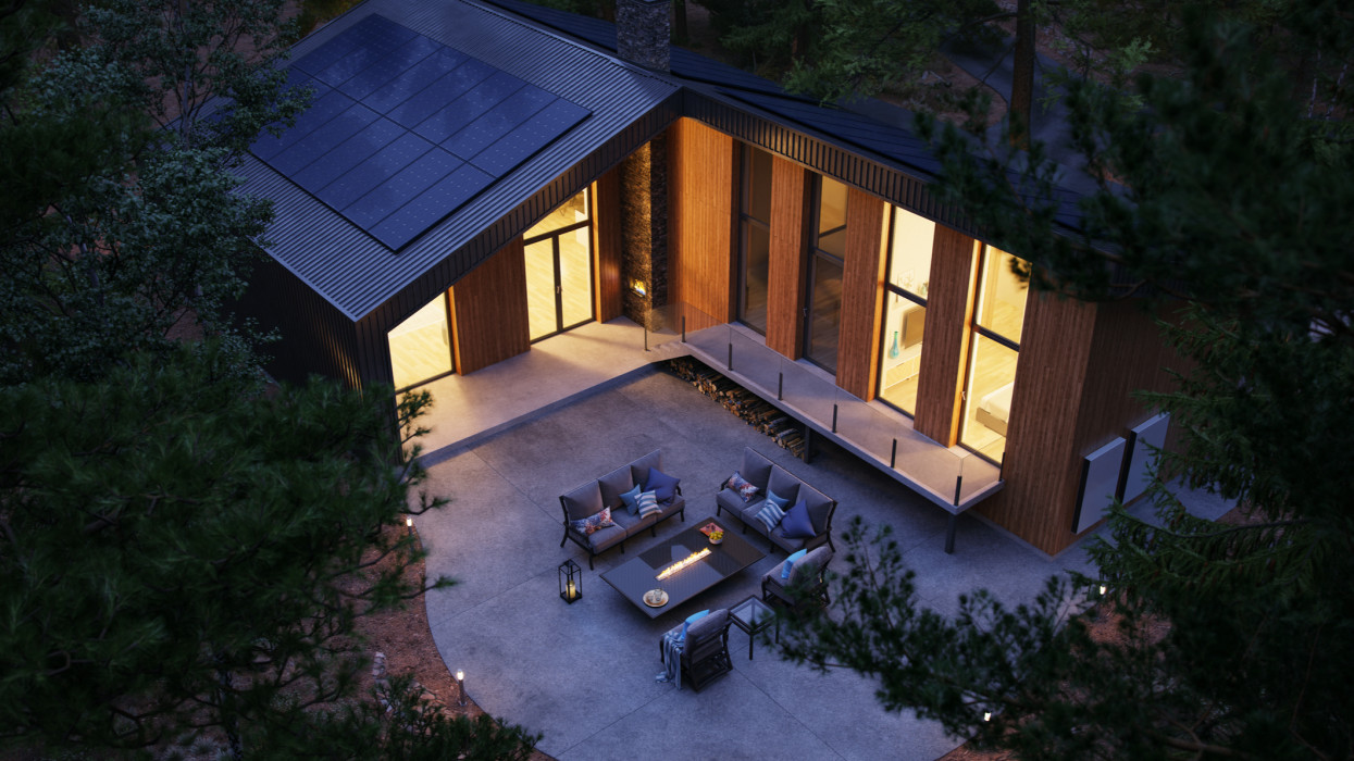 Modern forest house equipped with solar panels and an energy storage wall battery during dusk.
