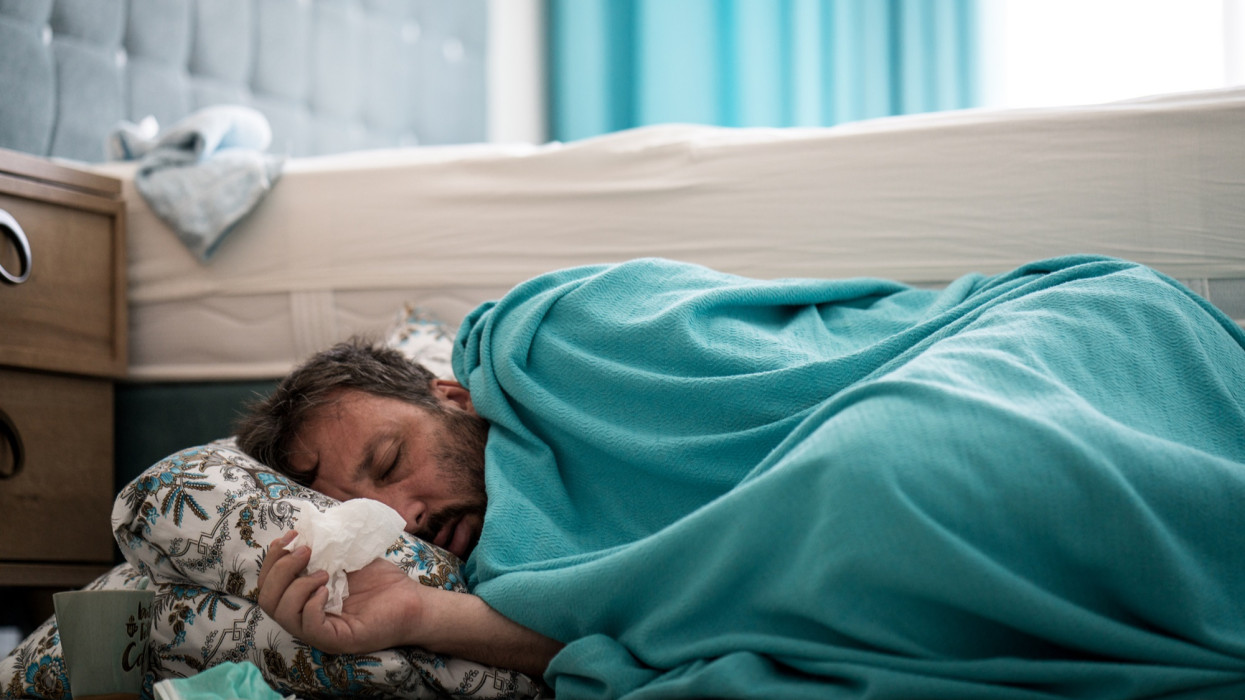Sick man with fever on ground in bedroom