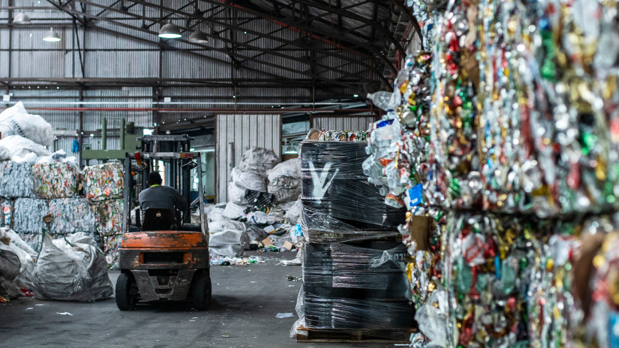 Wide shot of interior of solid waste processing facility full of blocks and bags of recycling materials