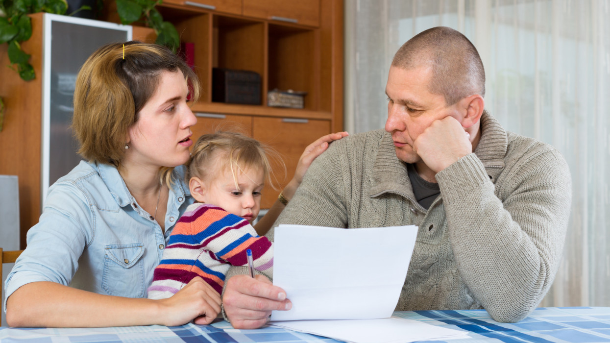 Worried family with child sitting with financial documents at home