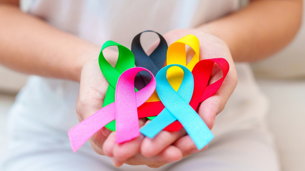 World cancer day, February 4. Hand holding blue, red, green, pink, black and yellow ribbons for supporting people living and illness. Healthcare and Autism awareness day concept