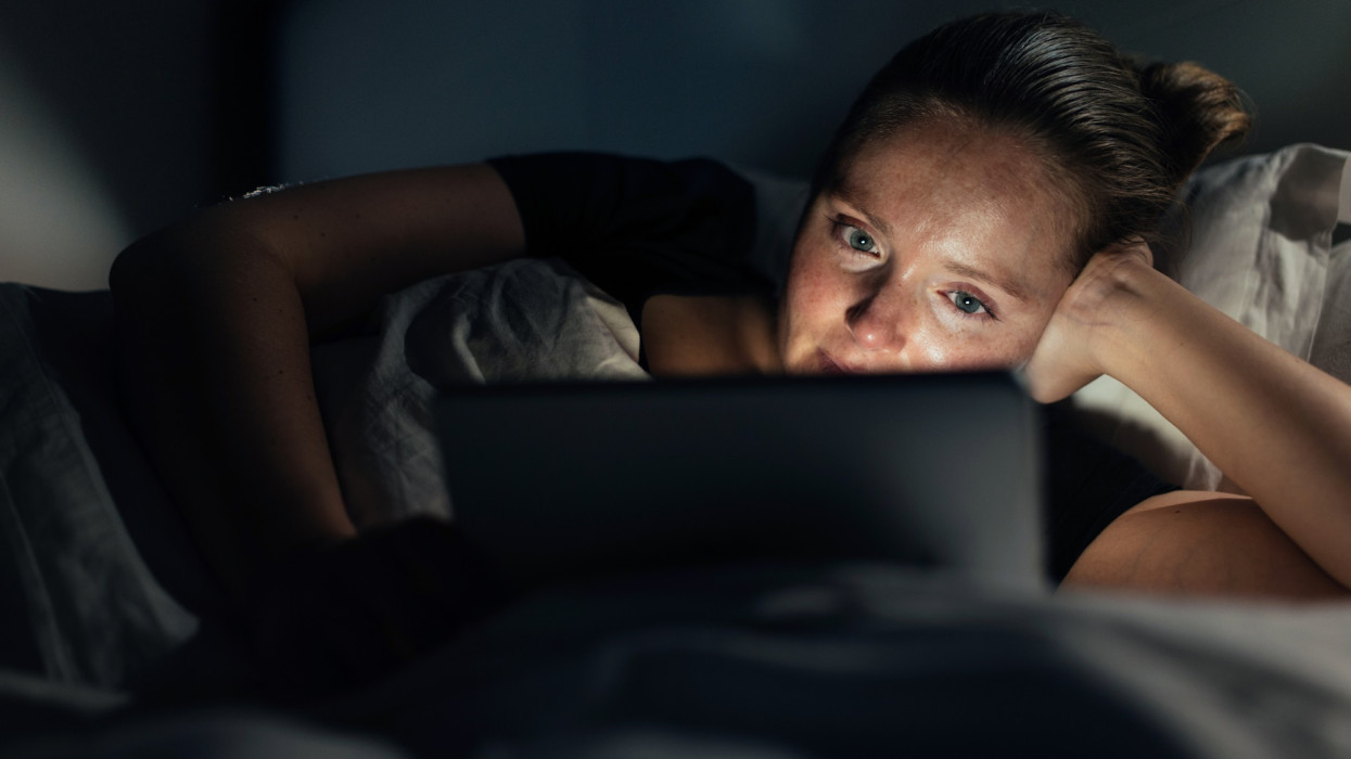 Woman using tablet pc, watching a movie late in the evening.