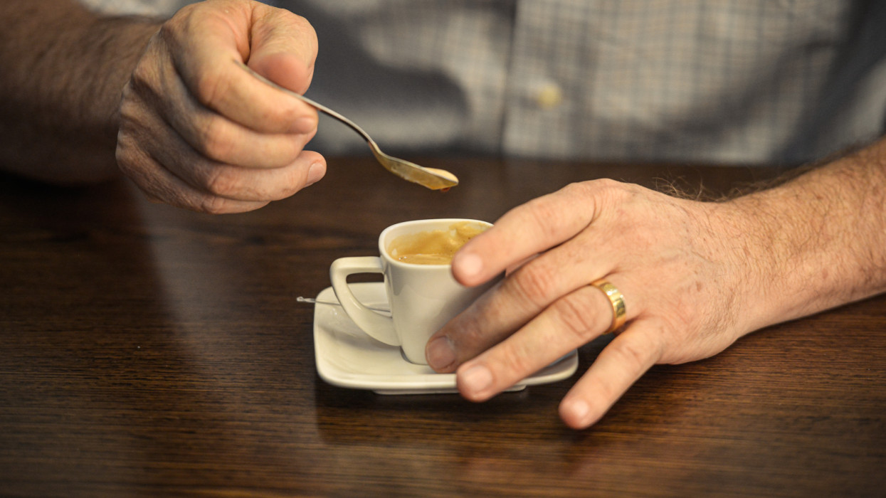 Hands of a man stirring a coffee before drinking.