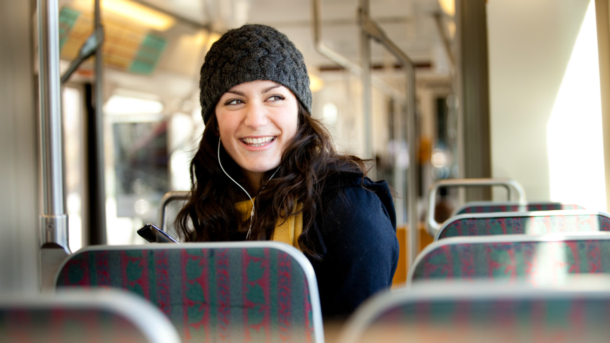 A woman listens to music while using public transportation to get around the city.