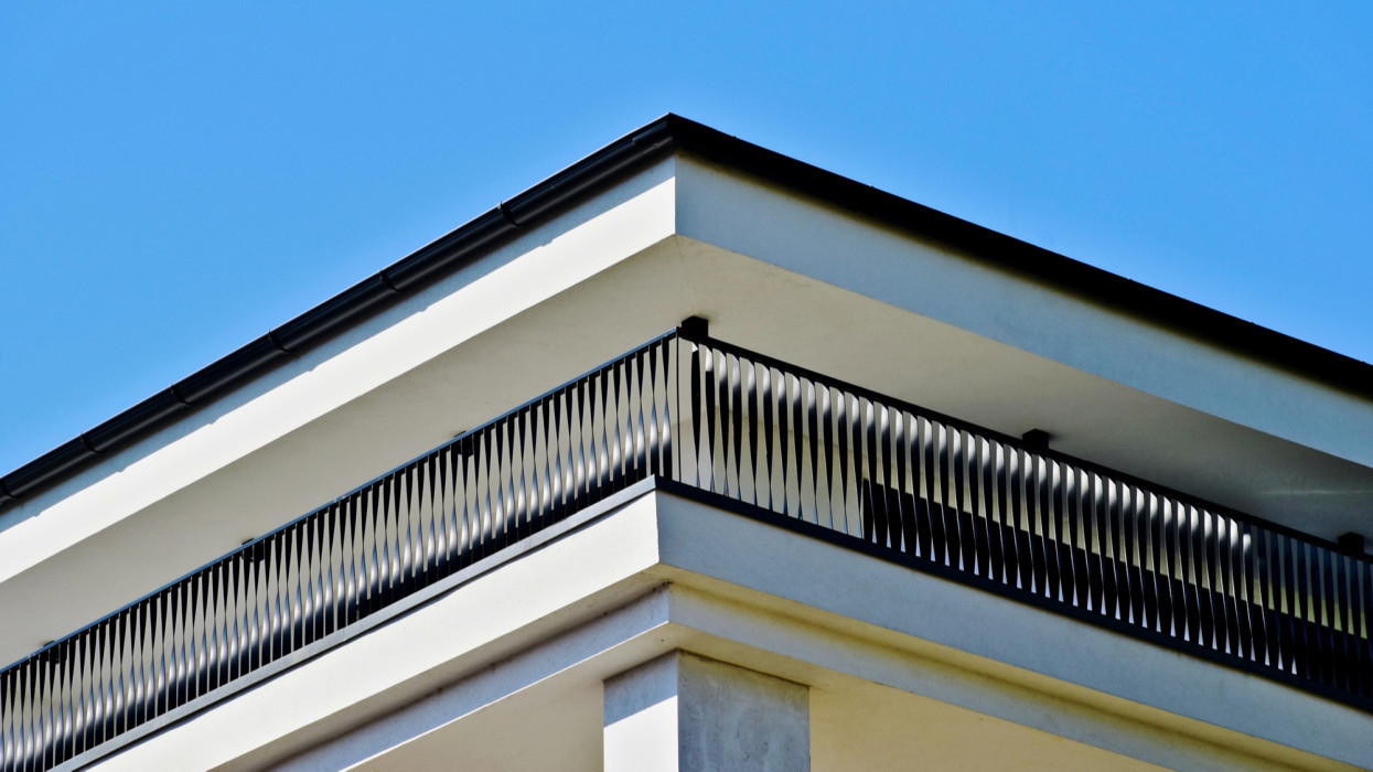 modern steel picket terrace balustrade closeup. white stucco exterior wall elevation. elegant pattern of twisted metal blades in a row. contemporary architecture. residential balcony and flat roof detail. blue sky.