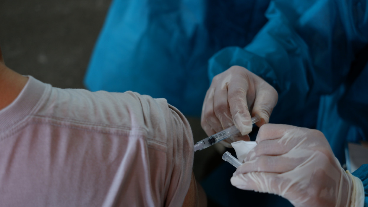 health worker injects vaccine into patients arm for Covid-19 Vaccine Booster. A vaccination concept photo.