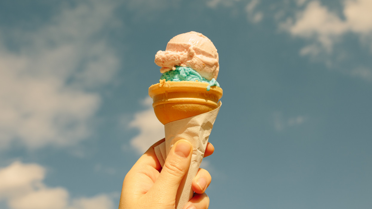 Hand holding tasty ice cream over the blue sky