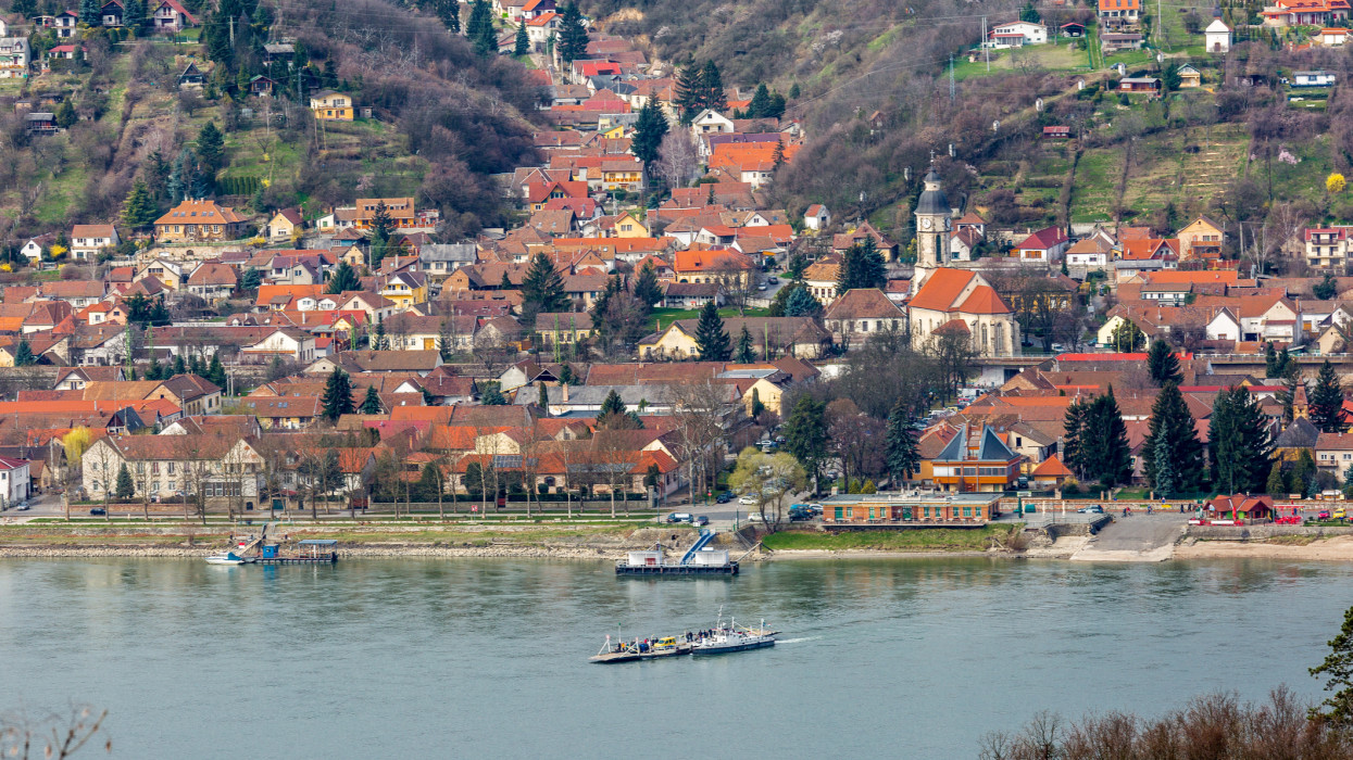 Beautiful view of small town Nagymaros in highlands on other side of Danube river, Hungary. Small ferry crosses the river