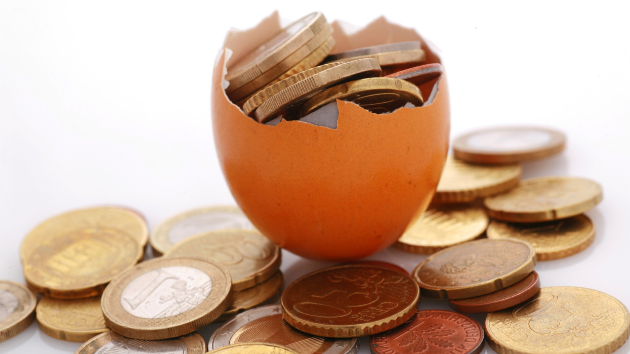 érmék tojáshéjban, a pénzügyi megtakarítások metaforája, törékeny pénzügyek,