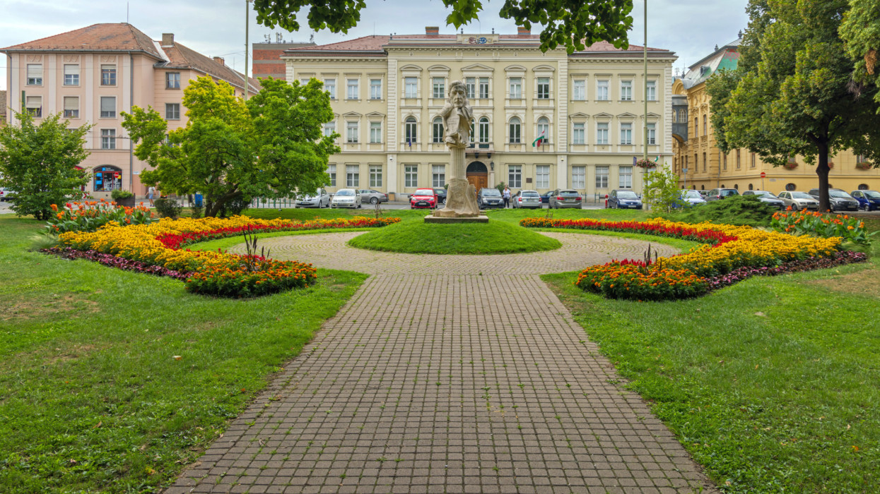Szeged, Hungary - July 30, 2022: Stone Statue of Klebelsberg Historic Landmark at City Park With Cultivated Garden.