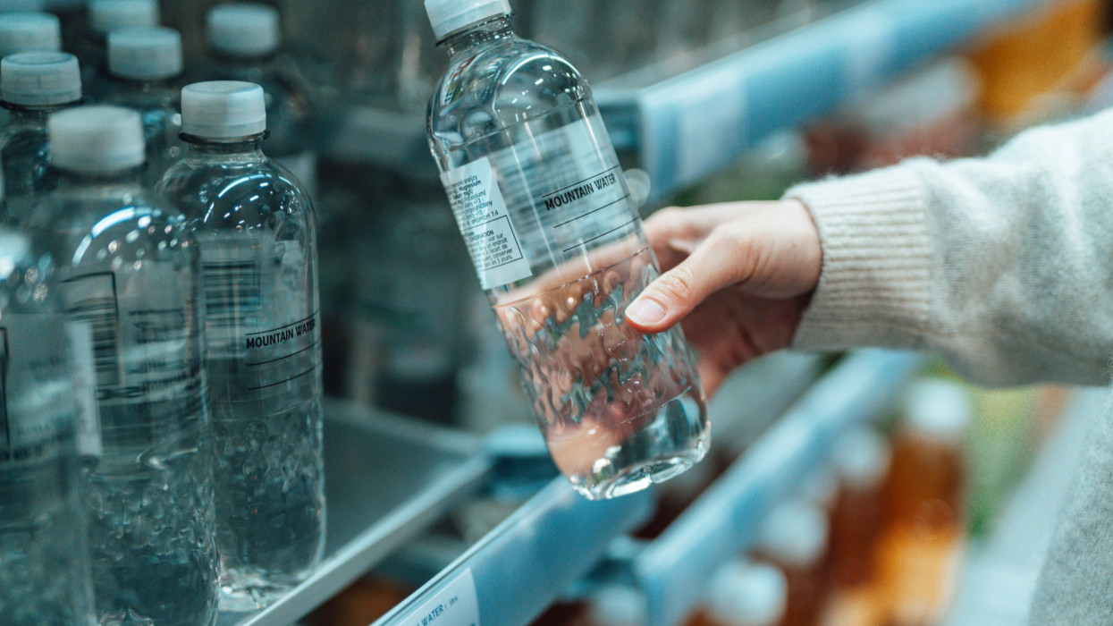 Close up shot of a woman buying bottled water in supermarket. BPA Free concept.