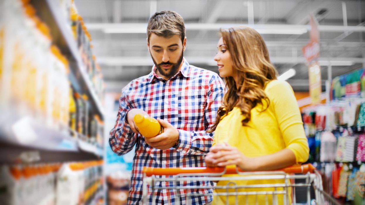 Young couple buying orange juice at supermarket.