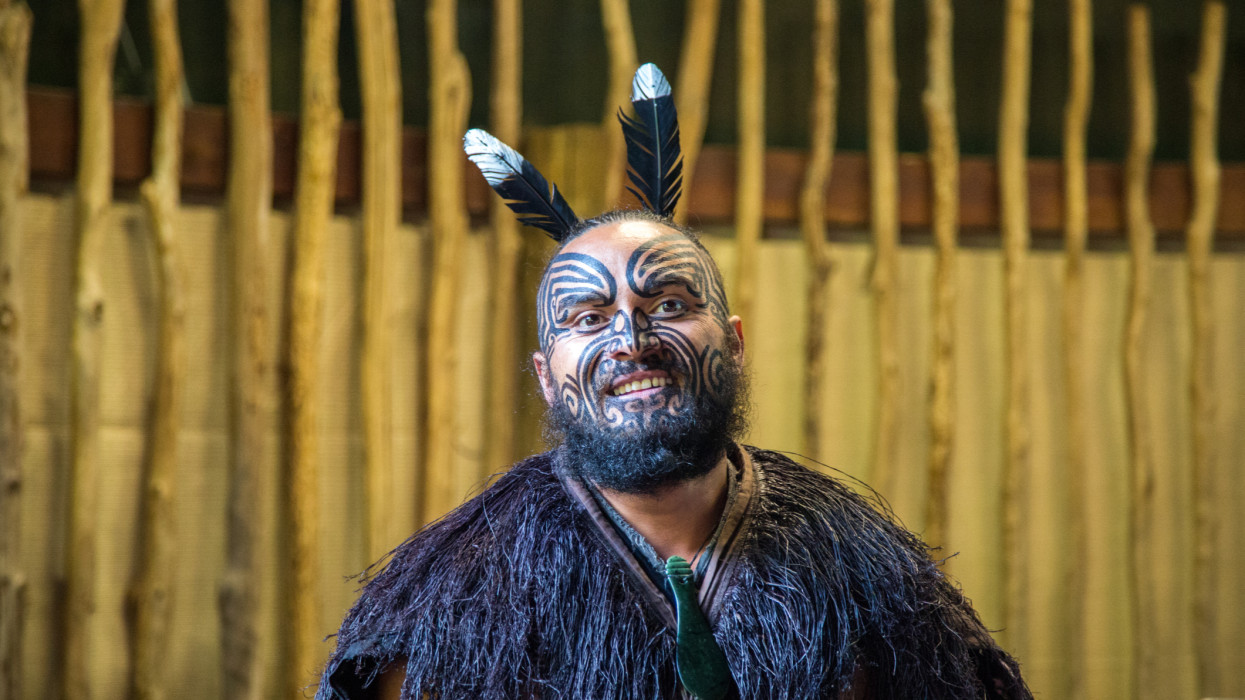 A portrait of a Maori man in traditional clothing and facial tattoos in Rotorua.