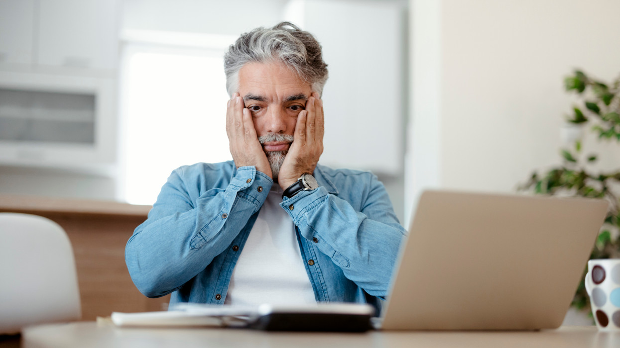 Mature man looking stressed and worried with credit card payments and home finances accounting costs charges taxes and mortgage in paying bills financial problems and debts