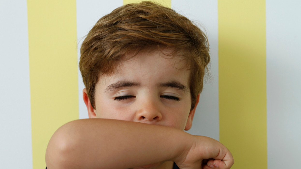 Boy coughing into his arm