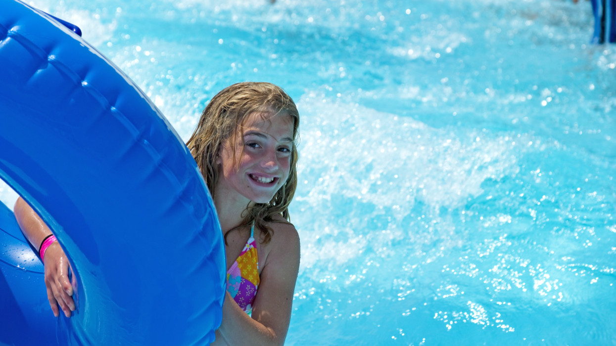 A teenaged girl enjoys a day at the wave pool in a water park.