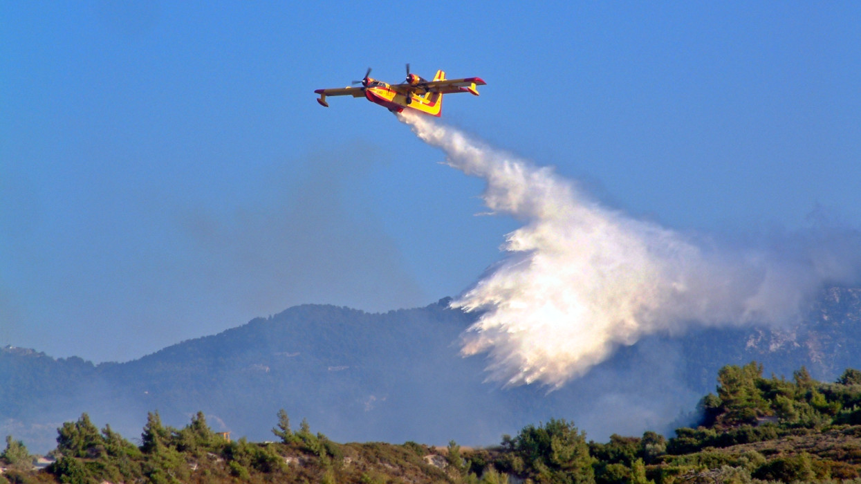 Greece, Europe - 2004: Fire Fighting Plane Drops Water On Forest Fire
