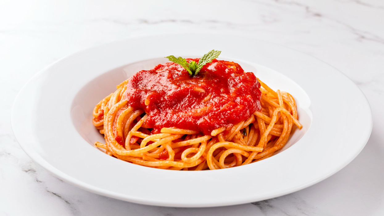 Előlnézetben spagetti paradicsomszósszal fehér háttéren.