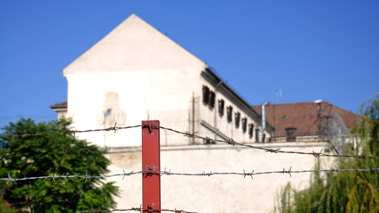 barbed wire fence in front of a prison building