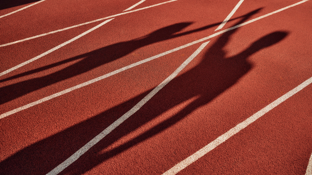 Egy pár sziluettje, akik a stadionban pacsiznak egymással. Reggeli gyakorlatok és kocogás. Sport és aktív életmód.