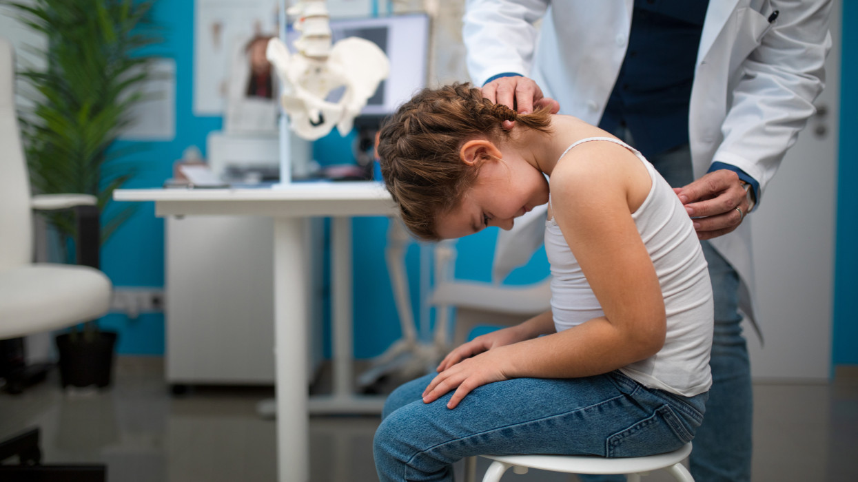 Little girl being examined by orthopedic doctor in his office.