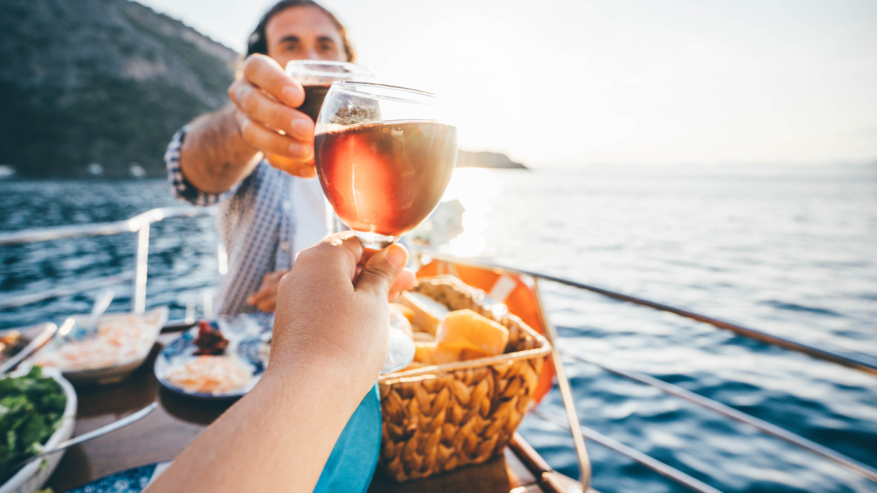 Friend drinking wine on the yacht at  sunset. Toasting on a yacht.