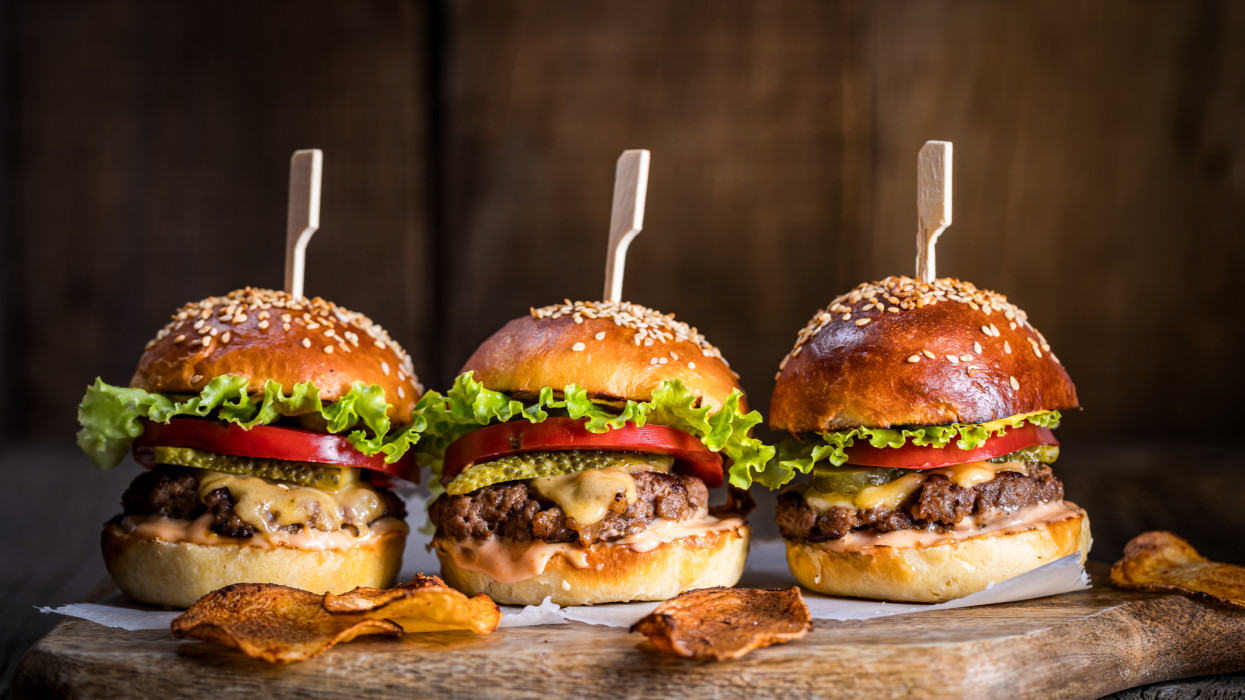 Cheeseburgers on wooden board and table in dark and moody light