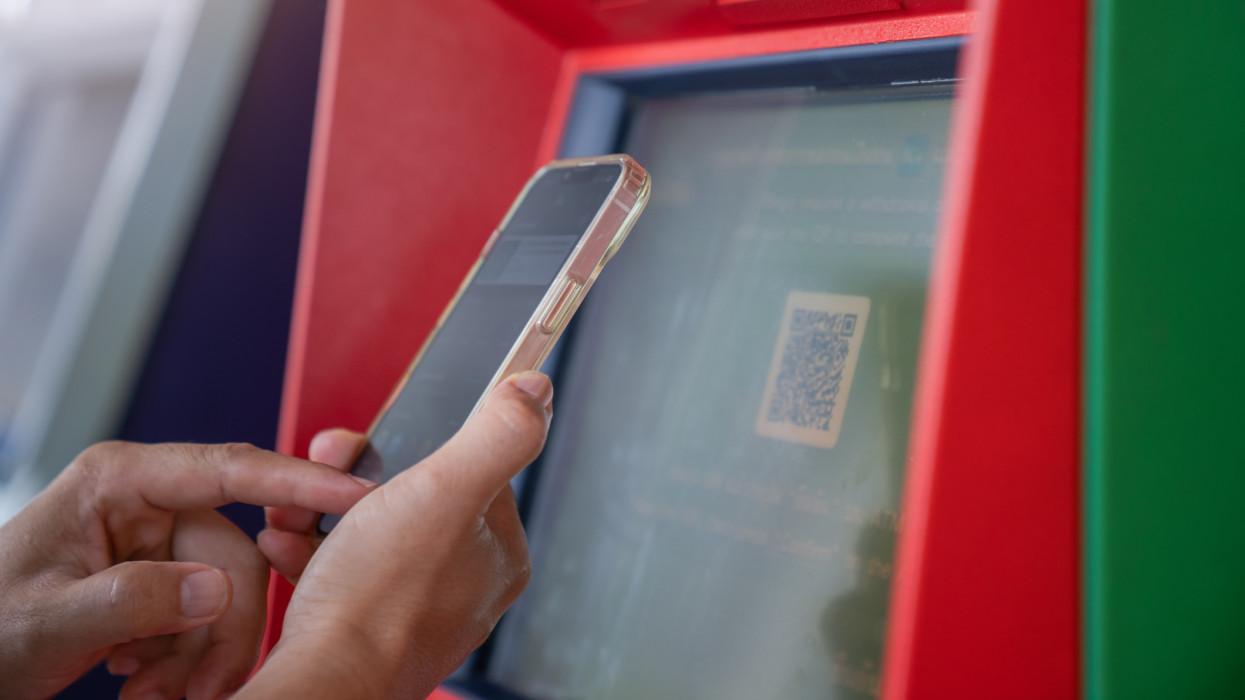 woman using mobile phone to scan ATM QR code