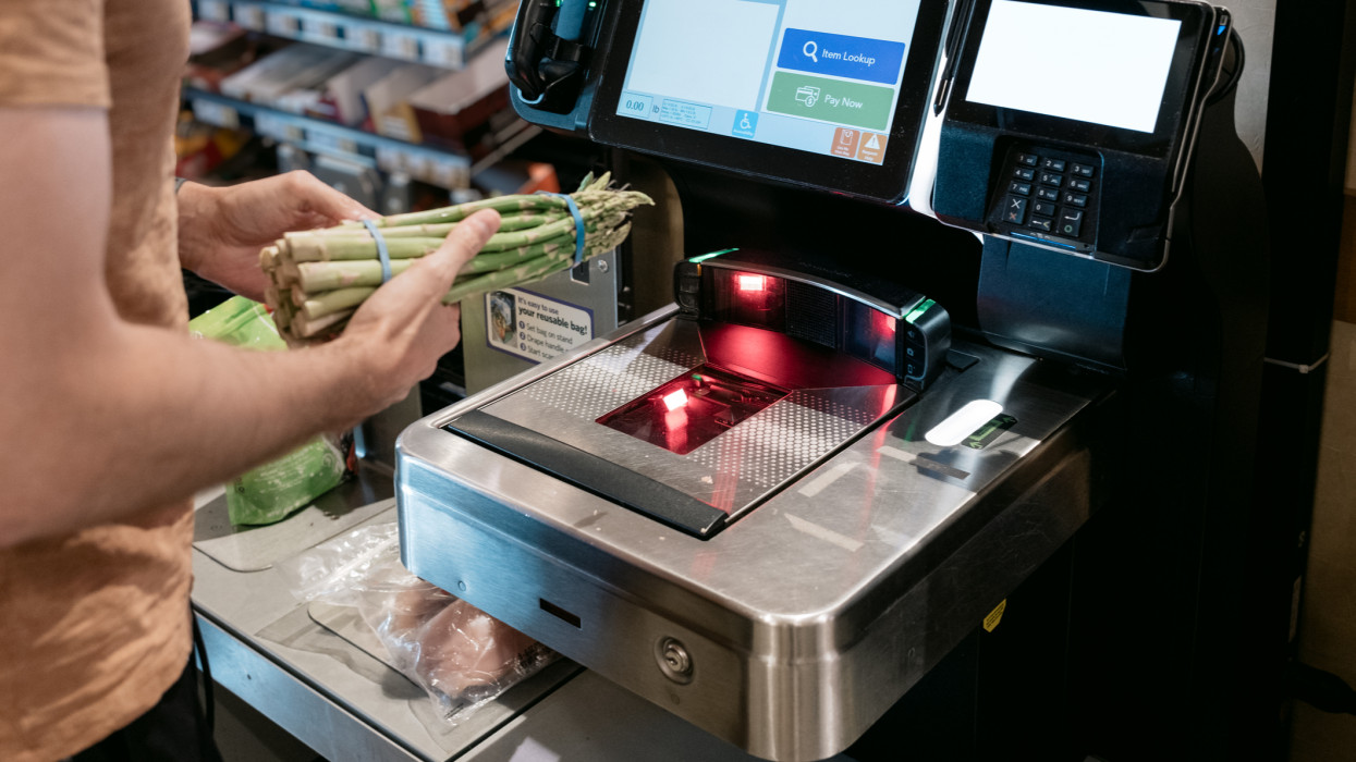 Close-up of unrecognizable man using self-checkout kiosk at grocery store