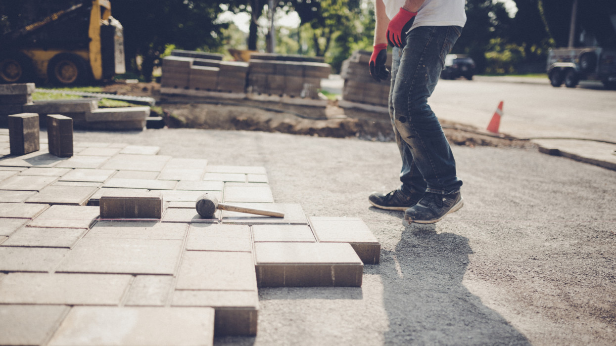 Young man installing paving stones for a new driveway