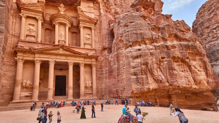 Turisták nézik a petriai kincstárat és fotózkodnak a tevékkel jordánia petra