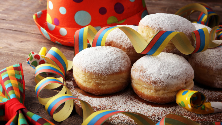 Carnival powdered sugar raised donuts with paper streamers. German berliner or krapfen