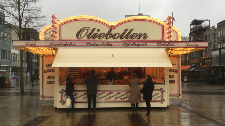 Almere Stad, Flevoland, Hollandia - 2017. december 30: Ismeretlen vásárlók vásárolnak mélyen sült fánkgolyókat, úgynevezett oliebollent, egy tipikus holland szilveszteri finomságot, egy ételstandnál.