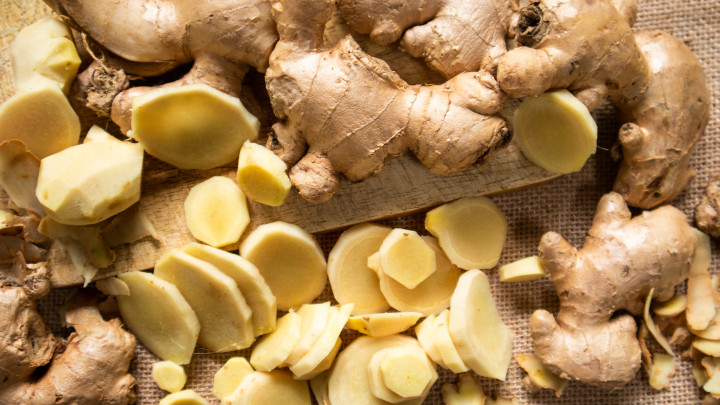 Gyömbérgyökér és szeletelt gyömbér egy faasztalon