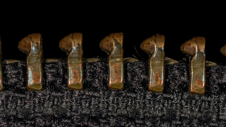 A fekete bőrdzseki záró cipzárjának részlete. Közeli makró helyi fókuszú felvétel. Vízszintes makrofotózás nézet.